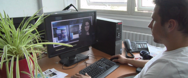 Illustration du pass transfrontalier, jeune homme à un bureau devant un ordinateur fixe